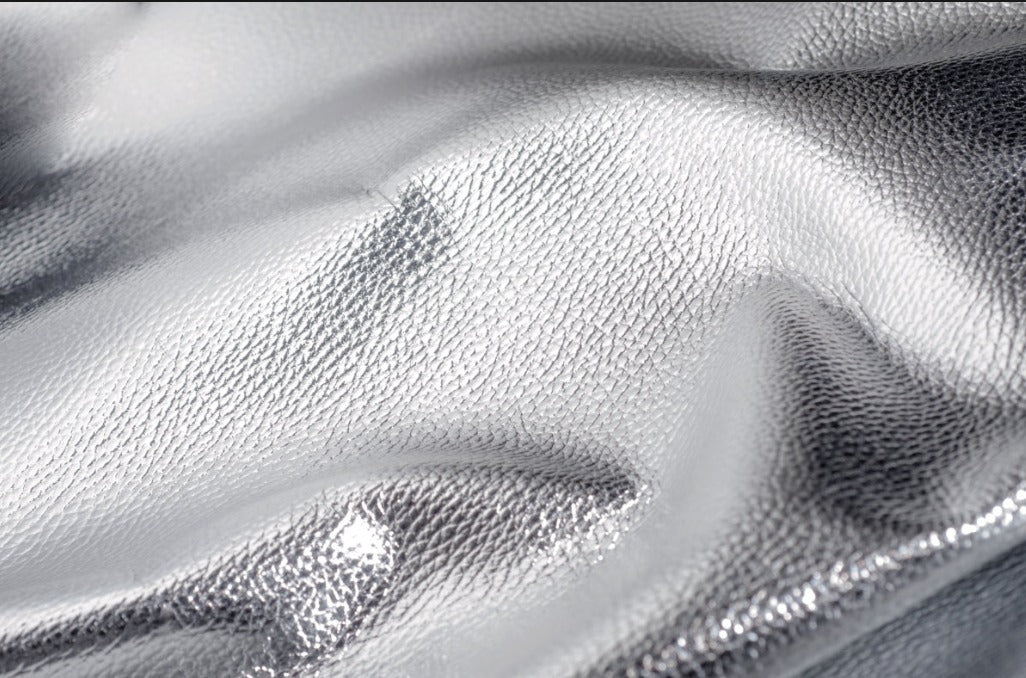 Close-up of shiny silver metallic leather with subtle textured grain and soft folds