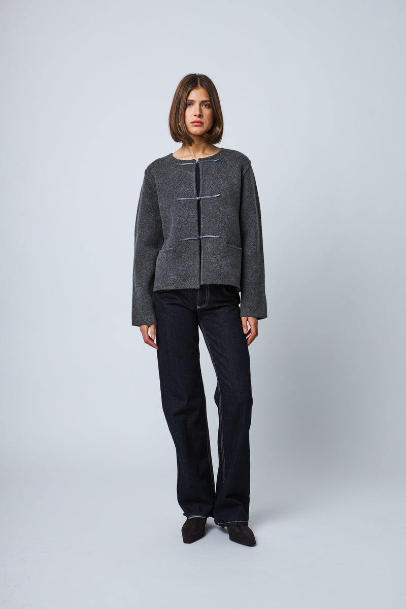 Dark grey wool cardigan with toggle closures, paired with dark straight-leg jeans