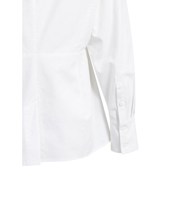 Close-up detail of white blouse hem and long sleeve cuff with buttons