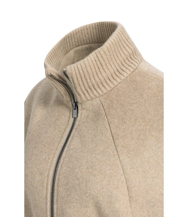 Close-up detail of beige wool mix poncho jacket showing ribbed collar and silver zipper