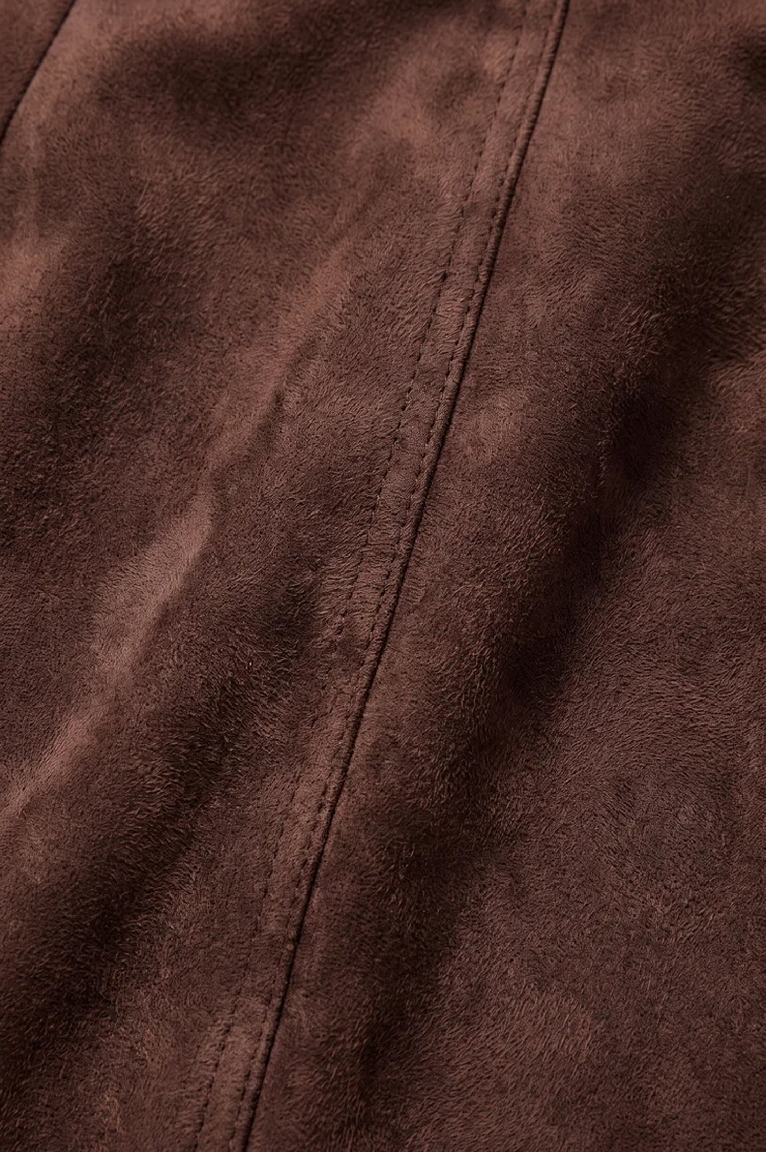 Close-up detail of dark chocolate brown suede fabric with visible seam stitching